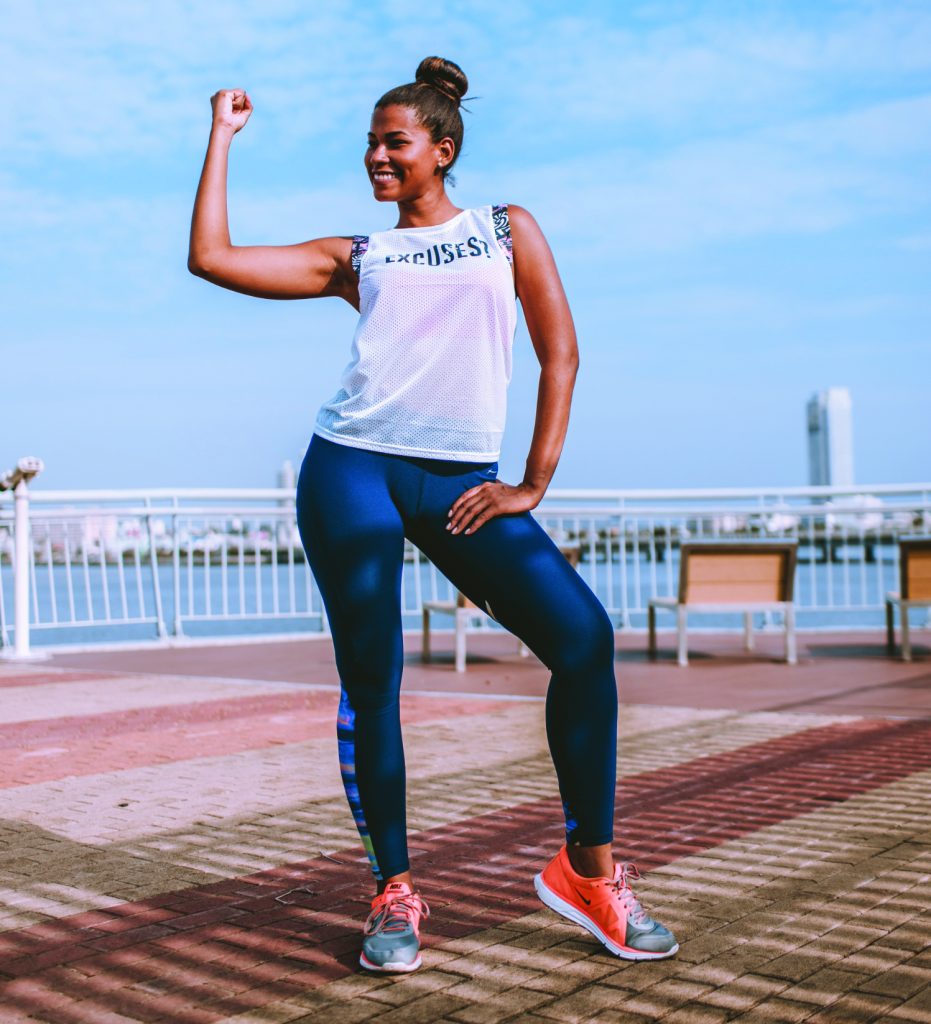 Girl flexing her arm near shoreline is happy with her interval workout routines